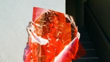 volto di donna dietro ad un foglio trasparente rosso - foto thought per unsplash.com